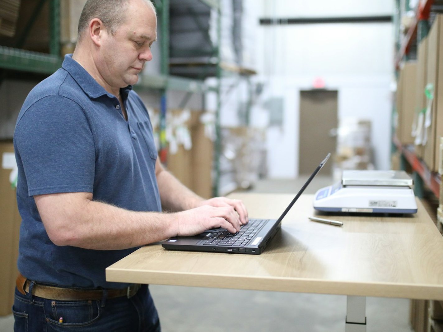 A plant manager reviewing verified candidate results on a laptop on the warehouse floor