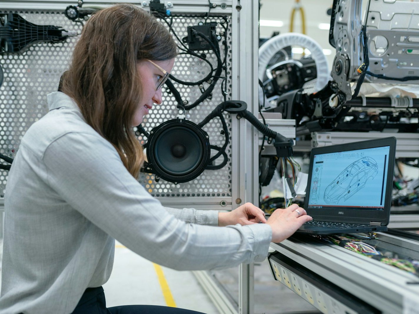 An engineering student working through a production-line scenario on a laptop in a vehicle systems lab